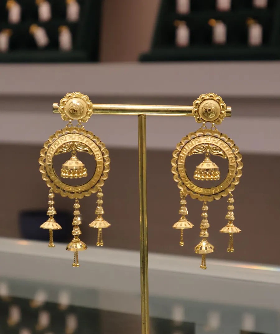 Round jhumka earrings with bell drops on a display stand