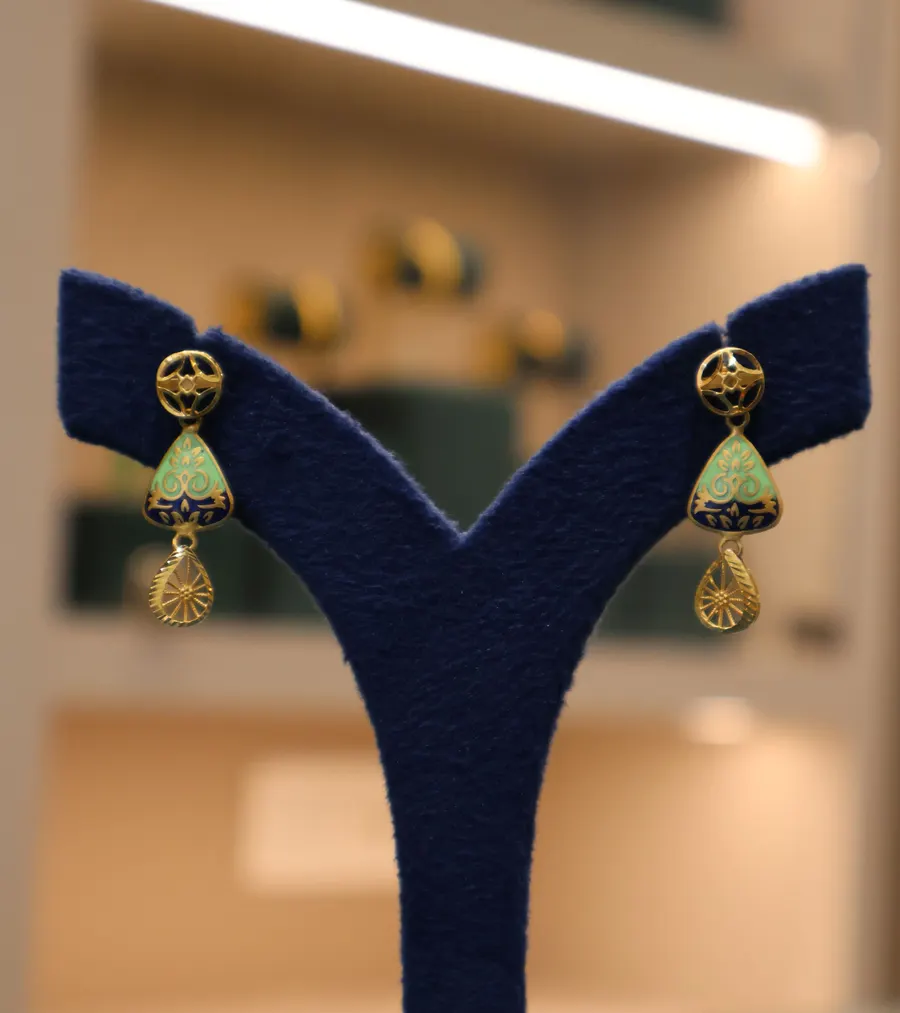 Gold drop earrings with mint enamel on a navy stand